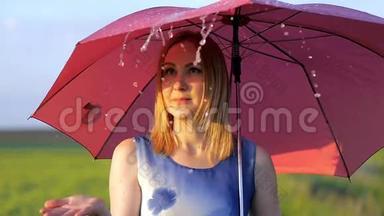一个美丽的女孩带着<strong>红伞</strong>在夕阳下微笑的情感绿色草地上微笑的女孩跳舞的肖像。